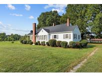 White house with brick chimney, surrounded by lush green lawn at 9847 Snow Camp Rd, Snow Camp, NC 27349