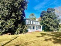 Two-story home with a wrap-around porch, mature trees, and a large yard at 303 High St, Oxford, NC 27565