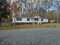 Single-wide mobile home with covered porch and gravel driveway at 6087 Zachary Ln, Oxford, NC 27565