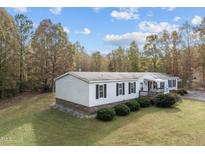 White single-story manufactured home with landscaped yard and deck at 60 Bogey Ln, Louisburg, NC 27549