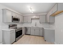 Modern kitchen with gray cabinets, stainless steel appliances, and marble countertops at 1207 Freeman Dr, Sanford, NC 27330