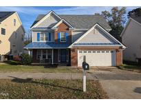 Two-story brick home with gray siding, a blue metal roof, and a two-car garage at 1433 Dexter Ridge Dr, Holly Springs, NC 27540