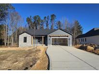 Newly constructed home with gray siding, stone accents, and a two-car garage at 15 Weathered Oak Way, Youngsville, NC 27596