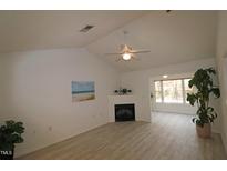 Bright living room features a corner fireplace, vaulted ceilings and laminate flooring at 11331 Involute Pl # 100, Raleigh, NC 27617