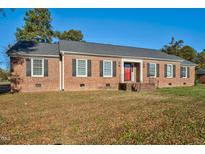 Brick ranch house with red door, landscaping, and a spacious yard at 1204 Breedlove Rd, Nashville, NC 27856