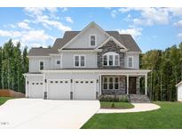 Two-story home with gray siding, stone accents, and a three-car garage at 613 Darian Woods, Holly Springs, NC 27540