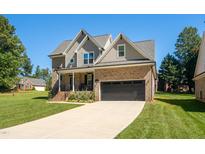 Two-story house with brick and siding, a large driveway, and landscaping at 407 Eagle Ct, Henderson, NC 27536