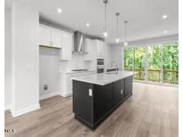 Modern kitchen with island, stainless steel appliances, and hardwood floors at 4505 Mint Leaf Ln, Raleigh, NC 27612