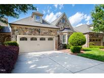 Stone exterior home with three-car garage and manicured landscaping at 4129 Gardenlake Dr, Raleigh, NC 27612