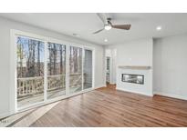 Bright living room with wood floors, fireplace, and sliding glass doors leading to deck at 4806 Cypress Tree Ln, Raleigh, NC 27612