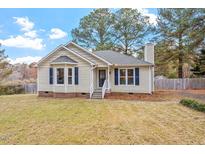 Beige house with blue window accents and a spacious lawn at 1024 Deep Canyon Dr, Clayton, NC 27520