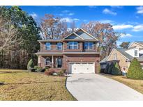 Two-story brick home with gray accents, a two-car garage, and a landscaped lawn at 105 Valleycruise Cir, Garner, NC 27529