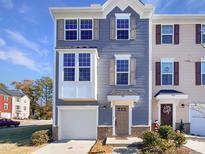 Two-story townhome with gray siding, a double garage, and a charming front porch at 901 Arnold Place Dr, Fuquay Varina, NC 27526