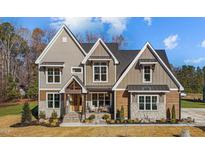 Two-story house with stone and wood accents, a covered porch, and a landscaped yard at 145 Wiggins Rd, Louisburg, NC 27549
