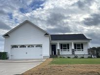 White house with a two-car garage and a nicely landscaped lawn at 130 Tulipfield Way, Benson, NC 27504