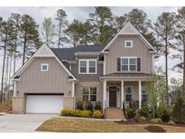Charming two-story home with a welcoming front porch and a brick and siding exterior at 9520 Wood River Dr, Zebulon, NC 27597
