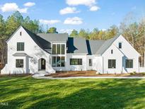 Two-story white brick home with a gray roof, large windows, and a landscaped lawn at 186 Evington Dr, Pittsboro, NC 27312