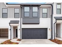 Modern townhome exterior with gray and white siding, a black garage door, and landscaping at 1042 Westerland Way # 213, Durham, NC 27703