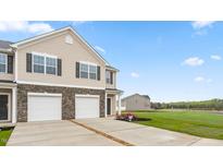 Two-story townhome with two-car garage, stone accents, and landscaping at 5512 Henley Ridge Dr # 191, Graham, NC 27253