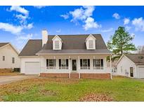 White house with brick accents, a porch, and a nicely landscaped yard at 2217 Maybrook Dr, Raleigh, NC 27610