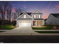 Two-story house with gray siding, white garage door, and landscaped lawn at 612 Emerald Bay Cir, Raleigh, NC 27610