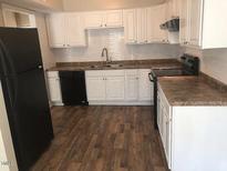 Bright kitchen with white cabinets, black appliances, and wood-look floors at 4600 Millstone Dr # D, Raleigh, NC 27604