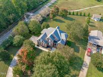 Aerial view of a two-story brick home with a large yard and circular driveway at 7601 Matherly Dr, Wake Forest, NC 27587