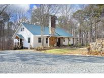 White farmhouse with green metal roof, stone accents, and a spacious gravel driveway at 540 Patterson Dr, Chapel Hill, NC 27516