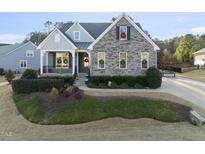 Craftsman style home with stone and siding exterior, landscaped yard, and inviting front porch at 1212 Broadwing Bend Ln, Wake Forest, NC 27587