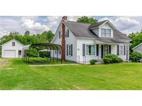White house with a carport, detached garage, and green lawn at 4470 S Nc Highway 62, Burlington, NC 27215