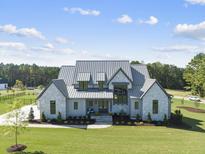 Modern farmhouse with metal roof and stone accents at 8917 Grand Highland Way, Wake Forest, NC 27587