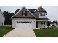 Two-story house with gray siding, white garage door, and landscaping at 102 Grinnel Loop, Sanford, NC 27332