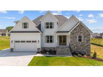 Two-story farmhouse style home with stone accents and a three-car garage at 125 Cotton Fields Ln # 26, Fuquay Varina, NC 27526