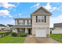 Tan two-story house with black window frames, a two-car garage, and a well-maintained lawn at 72 New London Hbr, Cameron, NC 28326