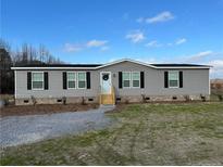 Gray manufactured home with black shutters, landscaping, and a gravel driveway at 441 Hayes Rd, Spring Lake, NC 28390