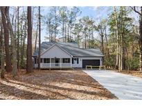 Newly constructed home with gray siding, a black garage door, and a front porch at 1374 Pennsylvania Ave, Sanford, NC 27332