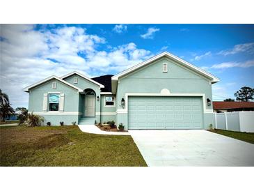 Charming one-story house with a light teal exterior, two-car garage, and landscaped lawn at 1590 Royal Rd, Venice, FL 34293
