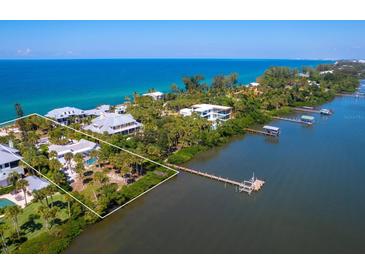 Aerial view of waterfront property with private dock and lush landscaping at 426 N Casey Key Rd, Osprey, FL 34229