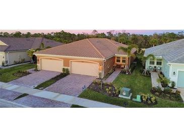 Two-car garage, light beige exterior, landscaped yard, and a paved driveway at 20676 Galileo Pl, Venice, FL 34293