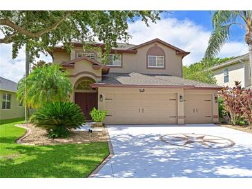 Two-story house with tan exterior, three car garage, and landscaped yard at 8108 Haven Harbour Way, Bradenton, FL 34212