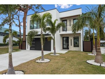 Contemporary two-story home featuring a sleek white exterior, black framed windows, and manicured lawn with palm trees at 2111 Hawthorne St, Sarasota, FL 34239