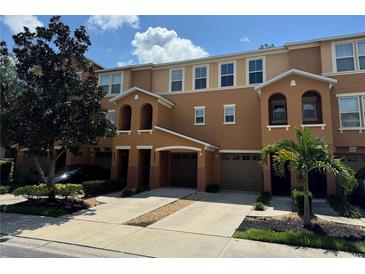 Tan three-story townhome with two-car garage, and landscaping at 8807 White Sage Loop # 1903, Lakewood Ranch, FL 34202