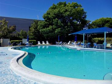 Community pool with lounge chairs and umbrellas at 305 30Th W Ave # A103, Bradenton, FL 34205