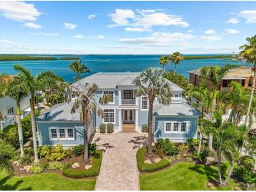 Stunning waterfront home with lush landscaping and a gray metal roof offering picturesque views of the bay at 757 Hideaway Bay Dr, Longboat Key, FL 34228