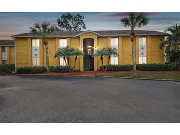 Two-story yellow building with palm trees and parking lot at 1967 Toucan Way # 201, Sarasota, FL 34232