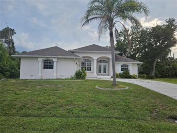 Charming single-story home with a well-maintained lawn and a beautiful palm tree in the front yard at 15 Tee View Pl, Rotonda West, FL 33947