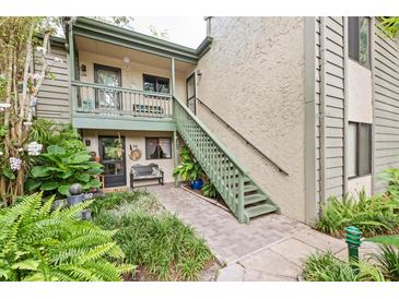 Front view of condo with stairs leading to entrance, lush landscaping, and a private patio at 1623 Pelican Cove Rd # 226, Sarasota, FL 34231