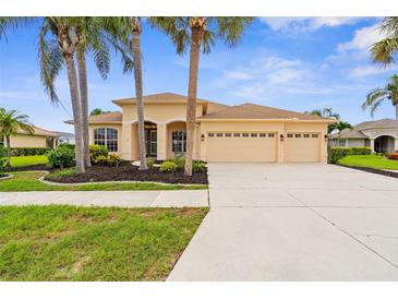Charming home featuring a well-manicured lawn, mature palm trees, and a spacious three-car garage at 310 Lake Tahoe Ct, Englewood, FL 34223