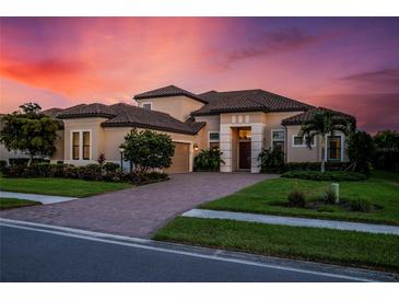 Stunning two-story house with a brick driveway, under a beautiful sunset at 5309 Greenbrook Dr, Sarasota, FL 34238