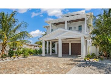 Two-story home with white exterior, two-car garage, and a brick driveway at 404 North Shore Dr, Anna Maria, FL 34216